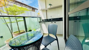 Ein Balkon mit Glastisch, Stühlen, Topfpflanzen und Blick zum Himmel.