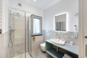 Une salle de bain avec une douche à parois de verre, des toilettes, un lavabo et un miroir.
