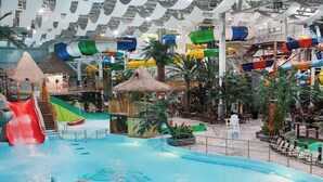 An indoor water park with slides, pools, and tropical-themed structures. - 13 guests / 4 baths | Luxury chalet + Spa | Quebec (Shannon)