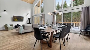 Un vaste espace de vie comprenant une table à manger pour six personnes, un canapé, une table basse et un tableau accroché au mur.