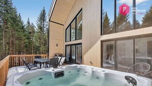 Un bâtiment moderne doté d’un jacuzzi, d’une terrasse en bois et de portes vitrées.