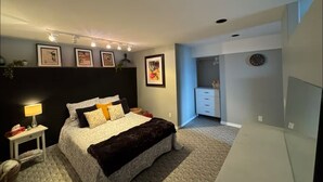 A bedroom with a bed, bedside tables, a nightstand, a dresser, a clock, and framed pictures on the wall. - Lake View Terrace with Pool (Osoyoos)