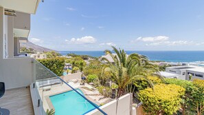 A poolside view with a clear view of the ocean and surrounding buildings. - Stunning 2-bedroom apartment in gorgeous Camps Bay - 5 mins from the beach. (Cape Town)