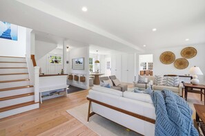A spacious living area with a staircase, a sofa set, and a television. - Historic Bones, Entirely New Soul | Designer Lux (Sandwich)