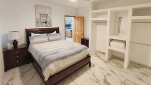 A bedroom with a bed, nightstands, a ceiling fan, a painting, and a wardrobe.