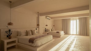 A modern bedroom with a large bed, bedside tables, a bedside plant, and a window with curtains.