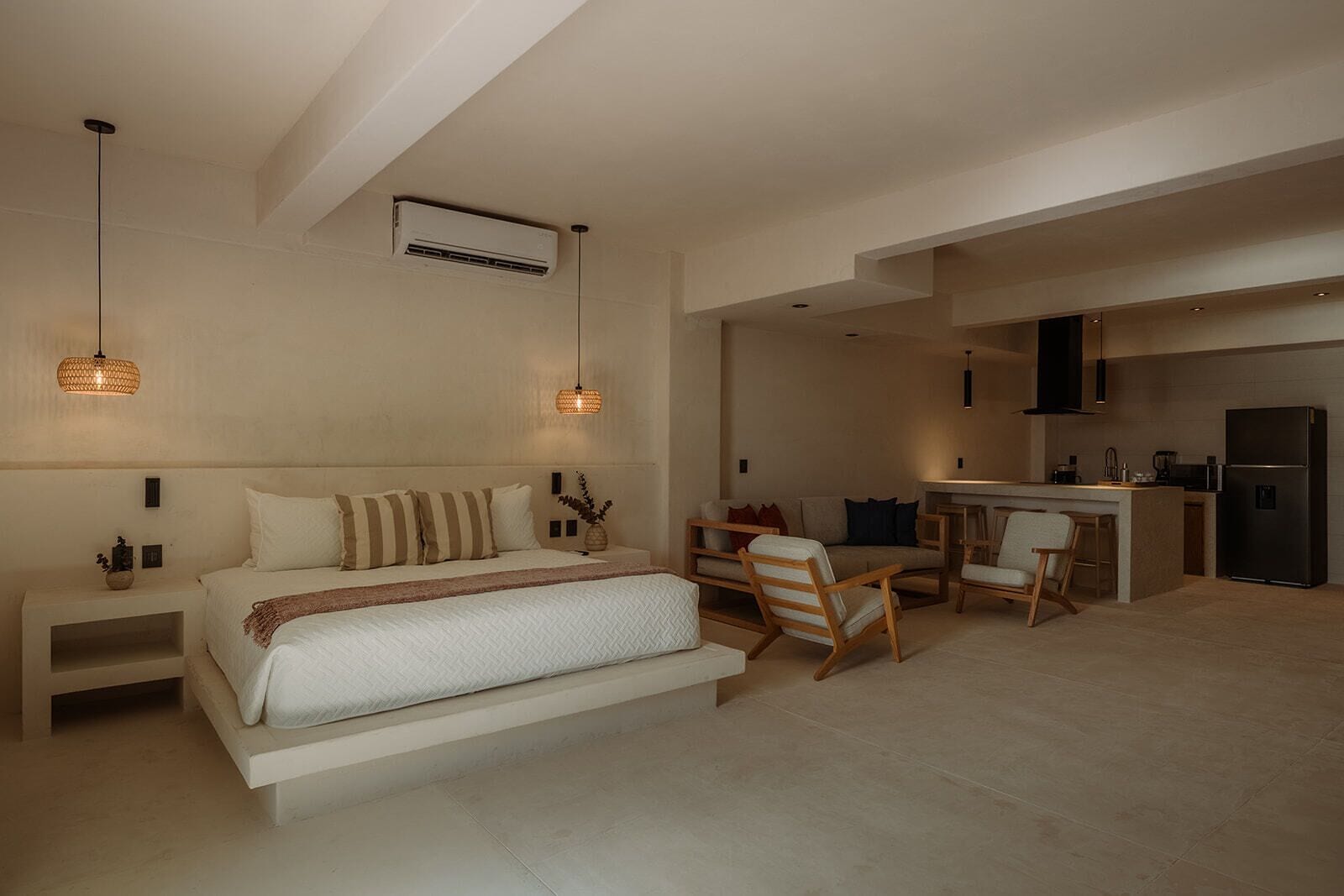 Une chambre moderne avec un grand lit, des tables de chevet, un bureau et un coin cuisine.