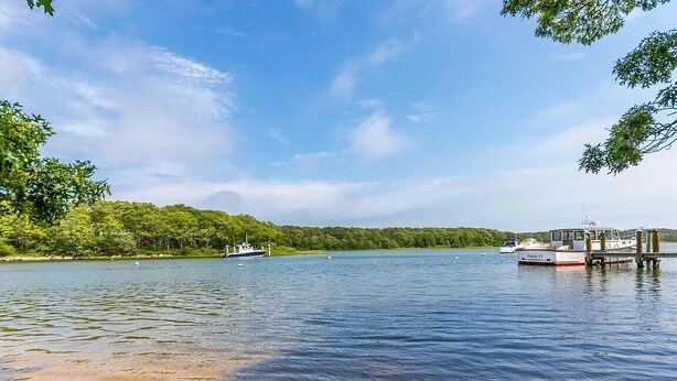 A calm lake with boats, a dock, and a forested shoreline. - Modern Cape Beach Escape - Classic Coastal Charm (Falmouth)