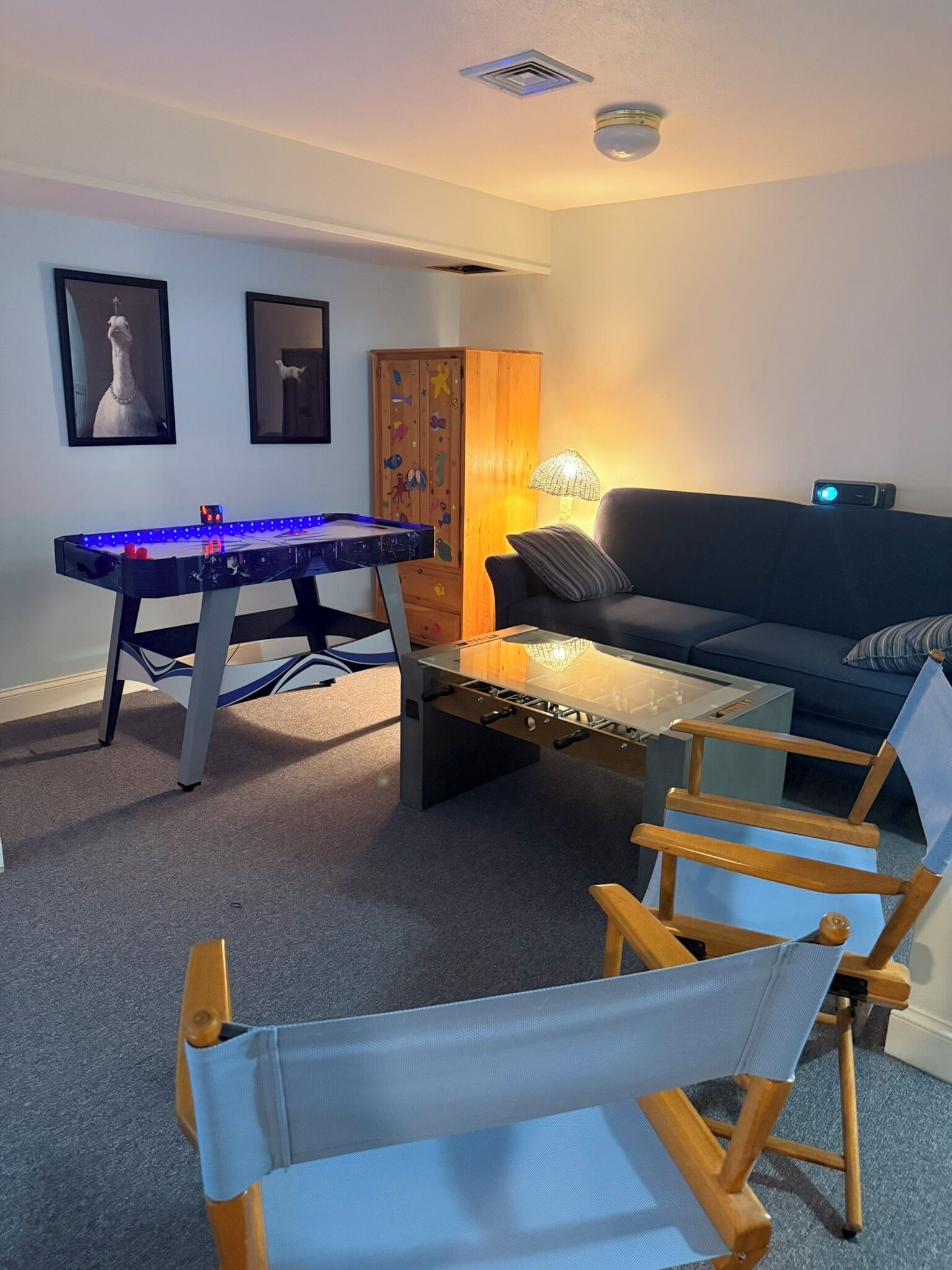 Ein Wohnzimmer mit Tischfußball, einer Couch, einem Couchtisch und einer Lampe.