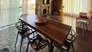 A spacious room with a high ceiling, a stone wall, a flat-screen TV, a dining table with chairs, and a sofa. - Cozy chalet in Conceição do Ibitipoca, 800 meters from the town center. (Conceição da Ibitipoca)