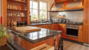 A modern kitchen with wooden cabinets, a granite countertop, a built-in microwave, and a stainless steel range hood. - Sunny Pool Villa at Vinkeveense Plassen | 20 Min from Amsterdam (Vinkeveen)