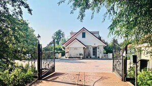 A gated entrance to a building with a paved driveway leading to a white house with a red roof. - Sunny Pool Villa at Vinkeveense Plassen | 20 Min from Amsterdam (Vinkeveen)