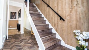 A staircase with wooden steps and a white handrail, leading to a room with a wooden floor and a radiator. - Fife Coast Stay with Parking & Garden in Rosyth - WiFi (Rosyth)