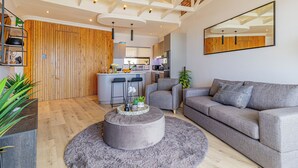 Un saló modern amb un sofà gris, una taula de centre rodona i una paret decorativa de fusta.