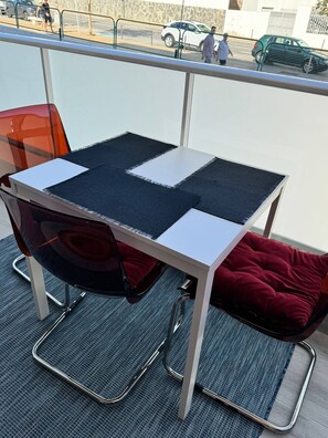 En balkon med et bord, stole og en rød pude.