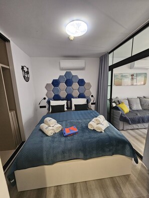 Et hotelværelse med en seng, en sengegavl med et geometrisk mønster, et vindue med udsigt og en loftlampe.