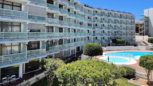 A multi-story hotel with balconies, a swimming pool, and a white picket fence. - Modern Premium Apartment Near Ccyumbo (San Bartolomé de Tirajana)