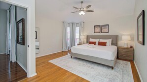 A bedroom with a bed, bedside tables, a ceiling fan, and a window with curtains. - 2 Homes • 8BR (sleeps 18) • Game Room & Backyards (Houston)