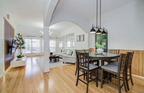 Un vaste espace de vie comprenant une table à manger, des chaises en bois et, au fond, une cuisine moderne.