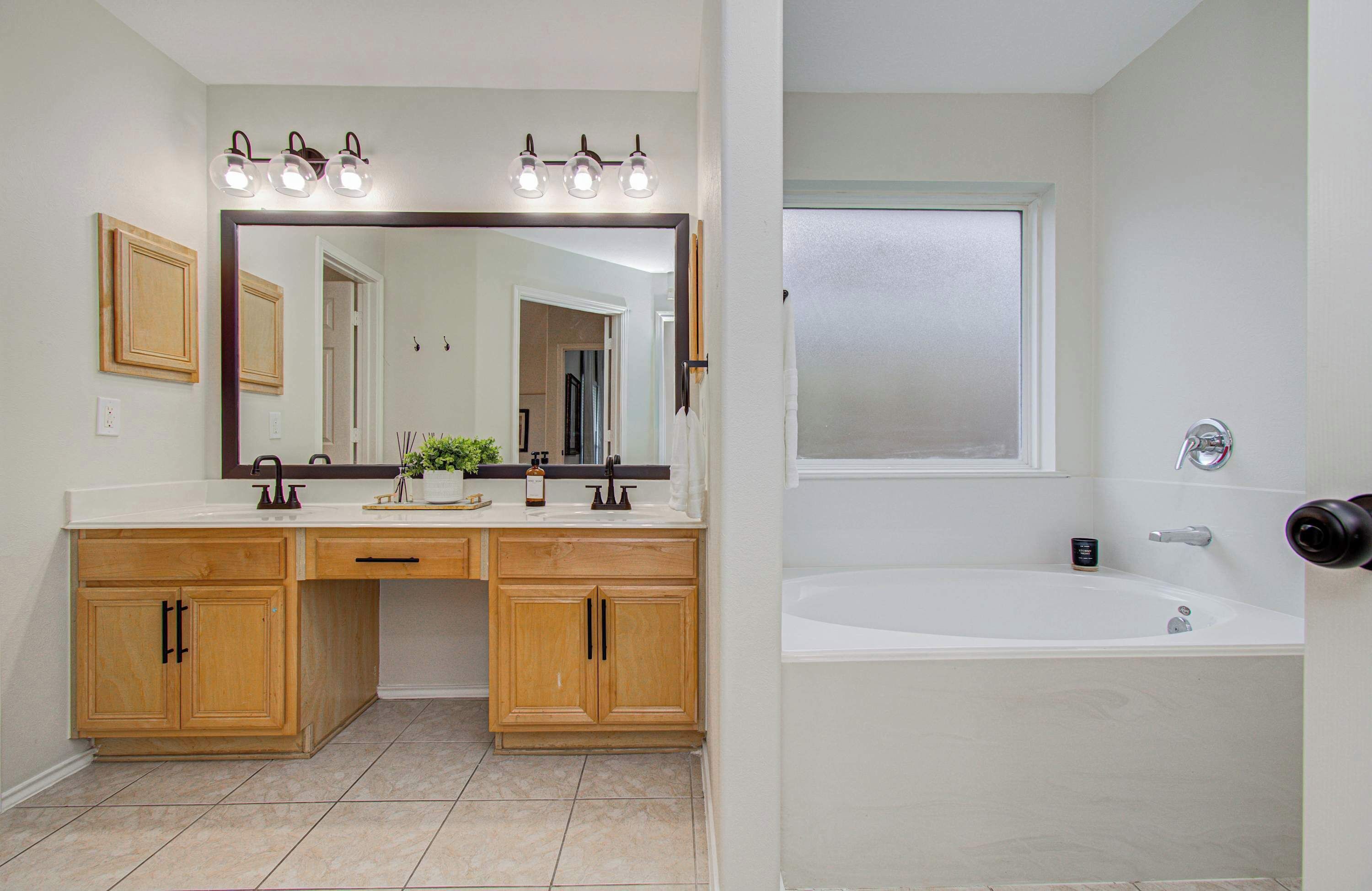 A bathroom with a double vanity, a large mirror, a bathtub, and a shower.