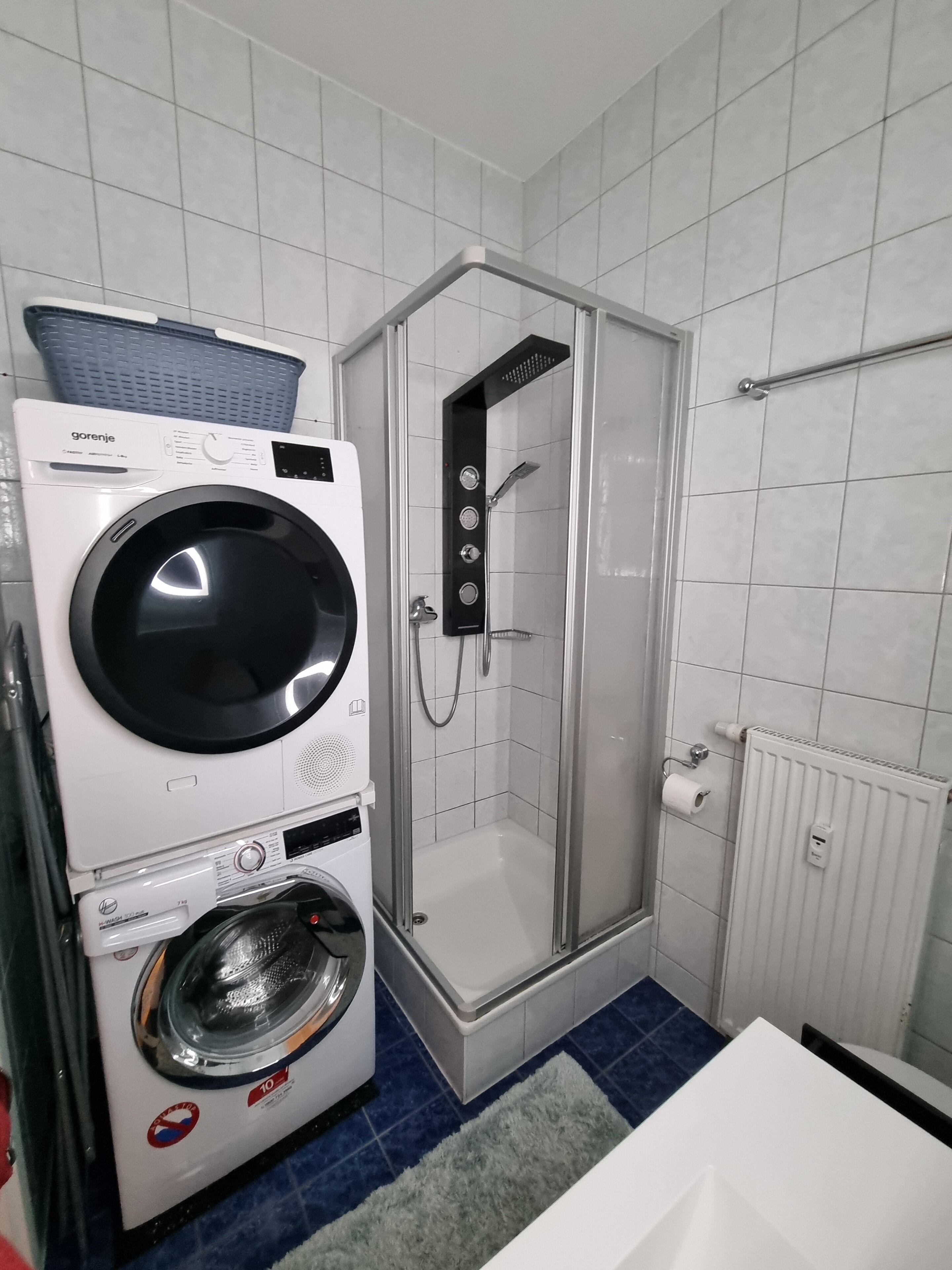 Ein kleines Badezimmer mit Waschmaschine, Duschkabine und Toilette.
