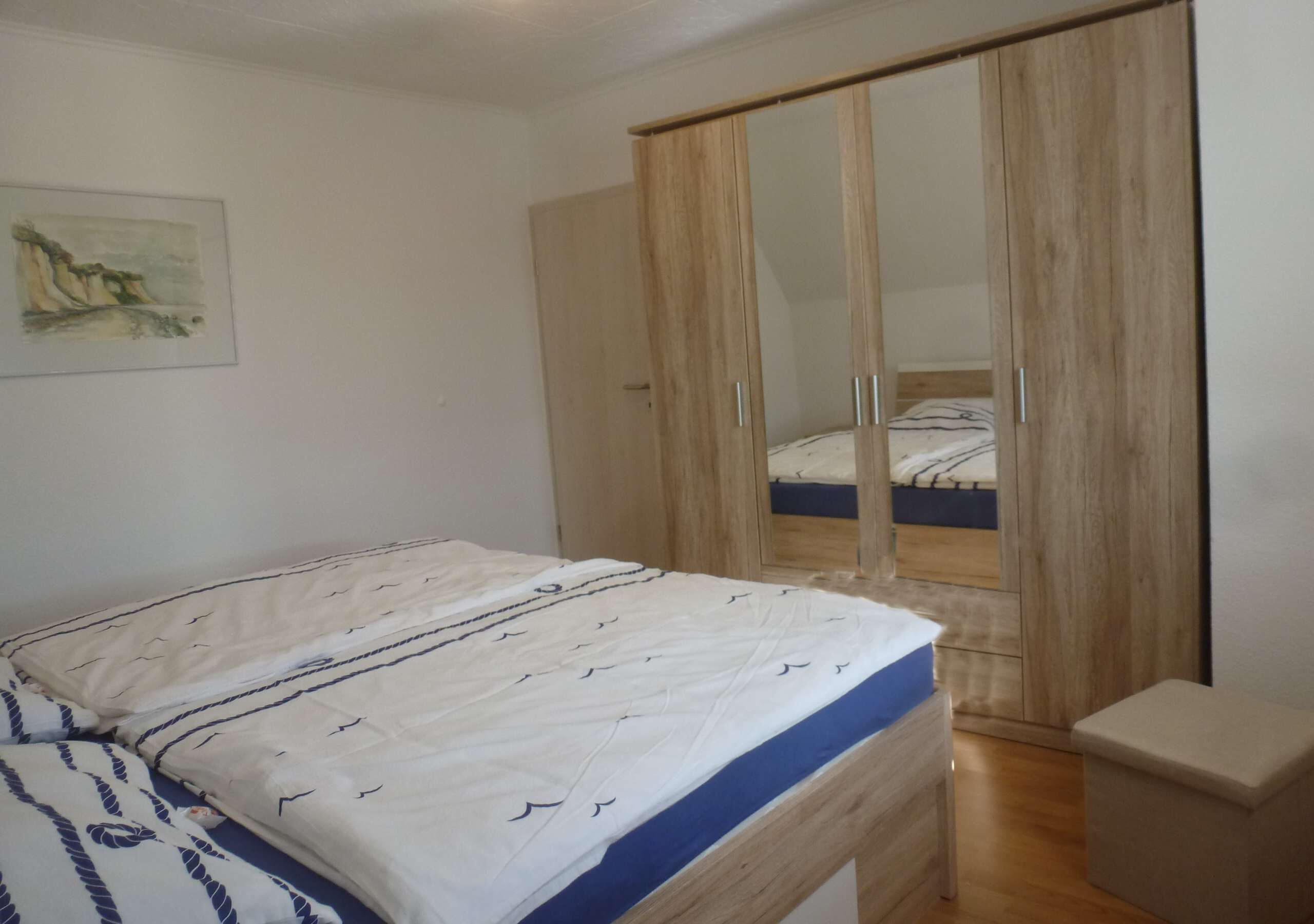 A bedroom with a bed, a wardrobe, and a small bedside table.