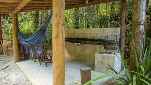 A wooden pergola with a hammock, a stone sink, and a bench. - Chal 3 com Churrasqueira e Ar a 200m da Praia (Prado)