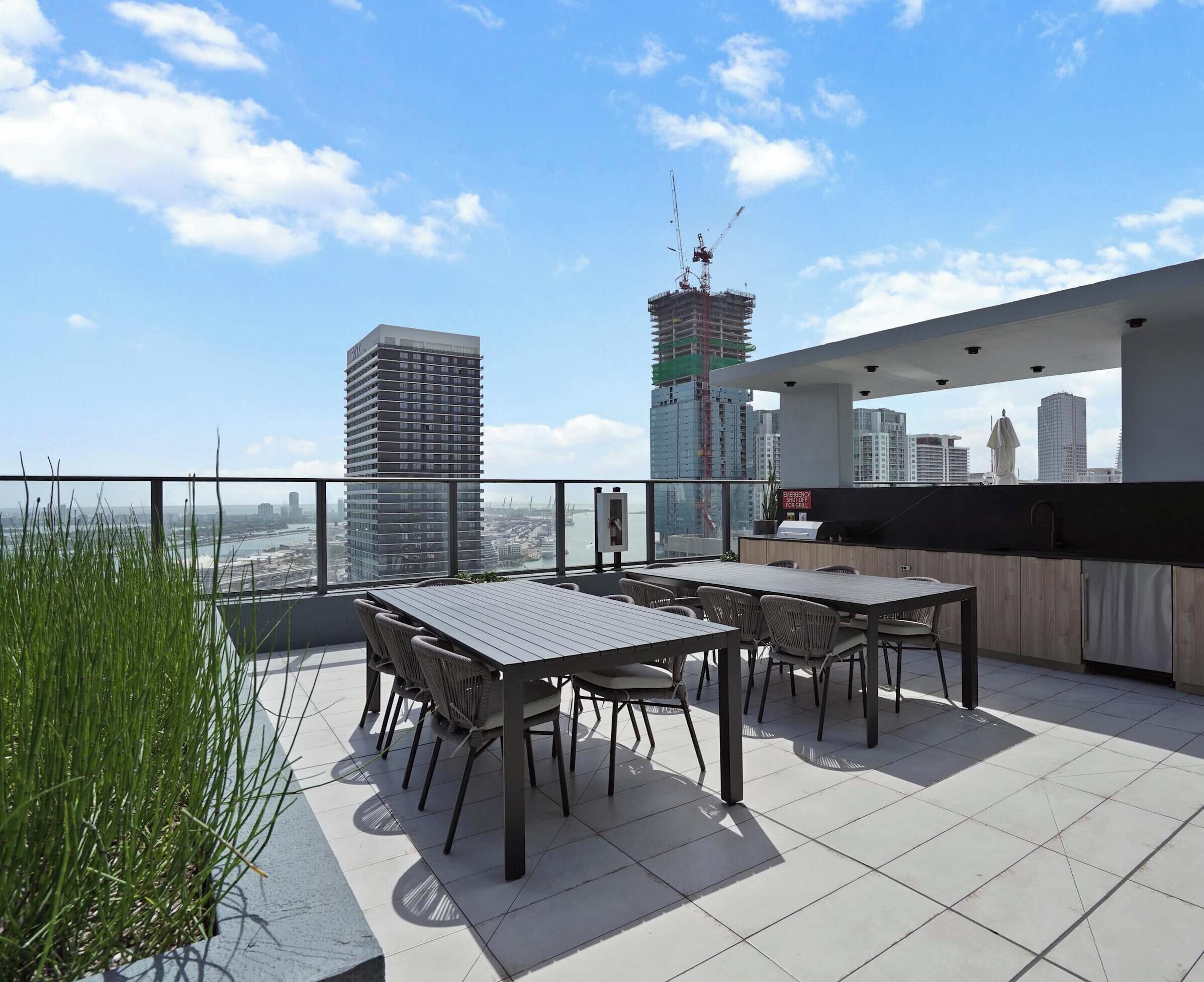 A rooftop terrace with a view of a city skyline, featuring a high-rise building and a construction crane.