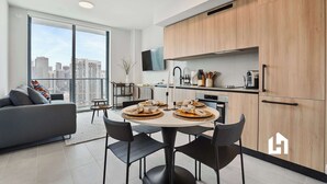 Een modern appartement met een eethoek, keuken en een groot raam met uitzicht op de stad.