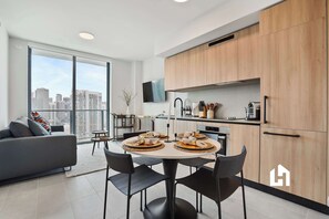 A modern apartment with a dining area, kitchen, and a large window with a city view. - 34th Floor High-Rise: Skyline Views & Balcony (Miami)