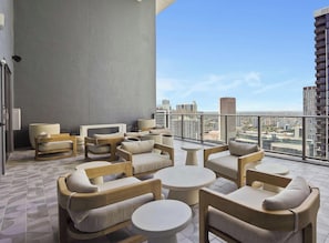 Ein Balkon mit Sitzgelegenheit, Blick auf die Stadt und ein Gebäude mit der Aufschrift 'RENT 305.800'.