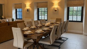 A dining room with a long table set for six, surrounded by six chairs, with a chandelier above. - Tranquil 7-bedroom villa in charming Dundrum perfect for groups and families. (Dundrum)