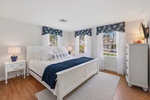A bedroom with a white bed, two bedside tables, a dresser, and windows with curtains. - Modern, Newly Renovated, 3-bed Peach Tree House (Chatham)