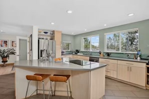 A modern kitchen with a central island, bar stools, and a view of the outdoors. - Central Boulder, Modern Comfort Close to CU, Chautauqua, and Pearl Street (Boulder)