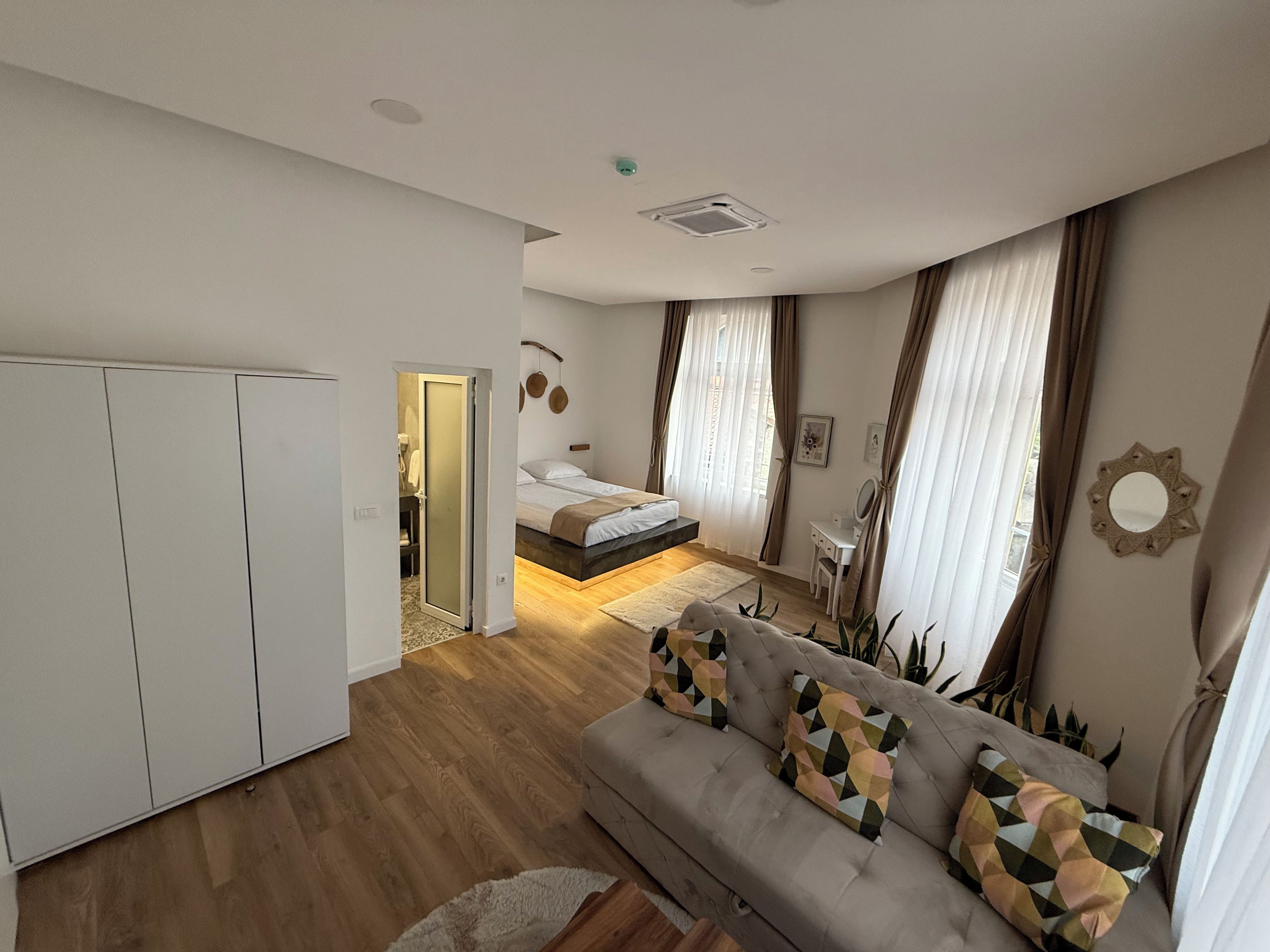 A modern bedroom with a bed, bedside table, and a view of the outside.