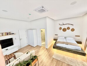 A modern bedroom with a bed, bedside tables, a TV, and a bookshelf.