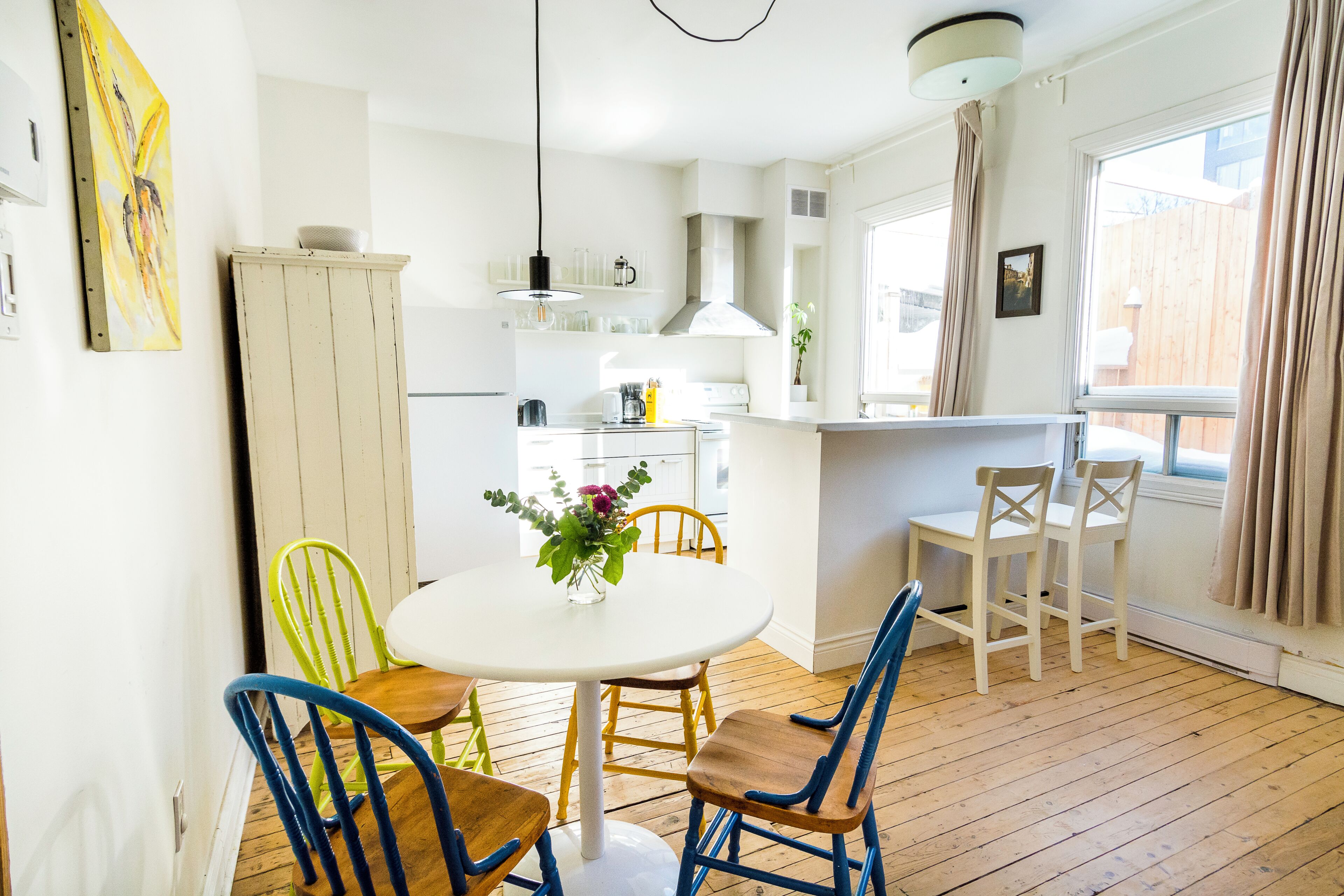 A kitchen with a dining table, chairs, and a window with curtains.