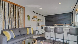 A modern living room with a grey sofa, a coffee table, and a patterned rug. - PeakView Lil Lux! Hot Tub & Mountain Views (Colorado Springs)