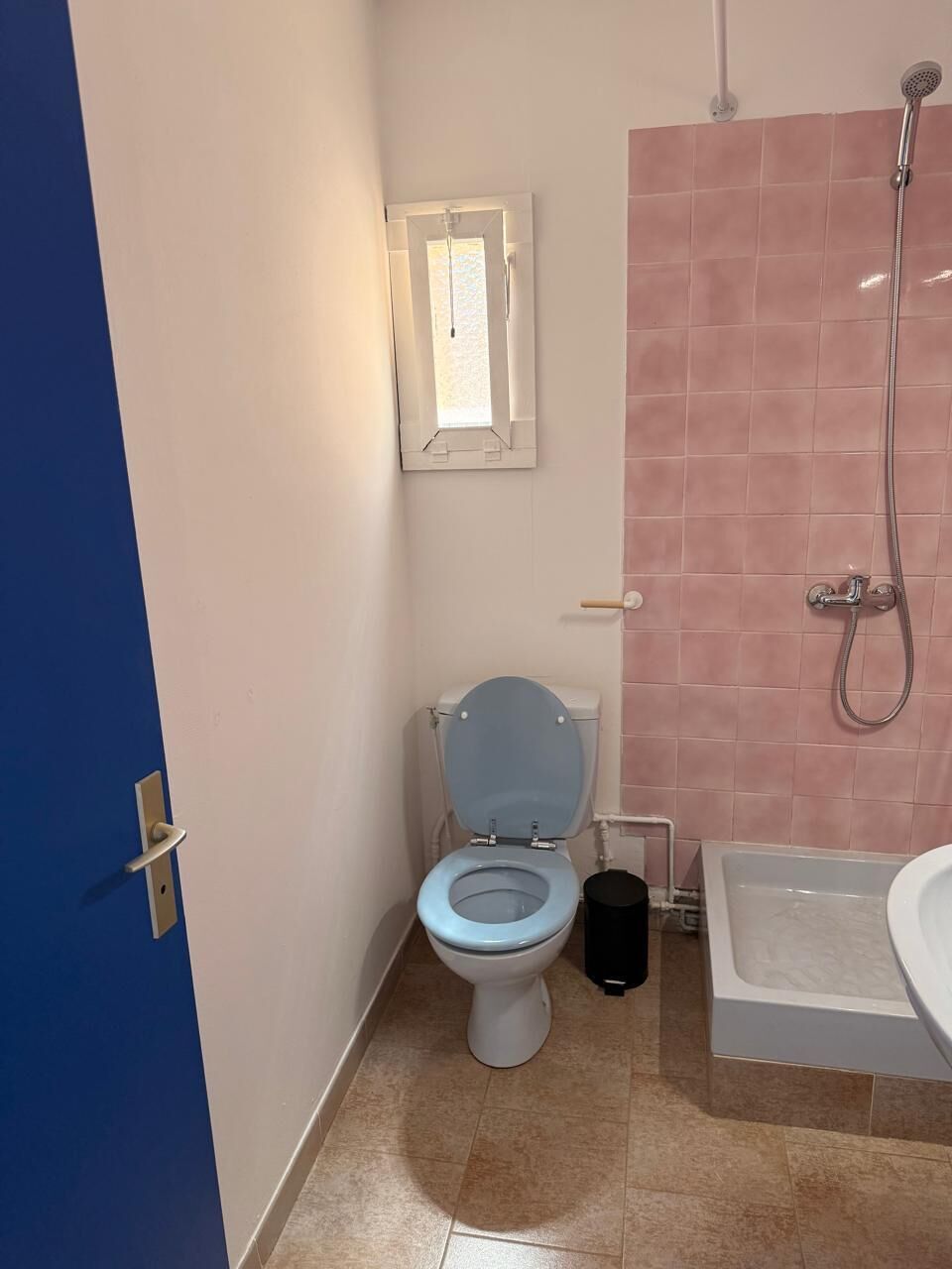 Et badeværelse med toilet, bruser og badekar.