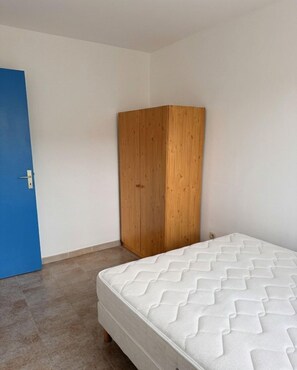 A bedroom with a bed, a wooden wardrobe, and a blue door. - Beautiful one-bedroom apartment in a house with a view of the sea, a 5-minute walk from the beach. (Calcatoggio)
