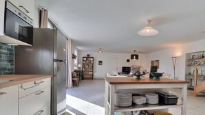 A modern kitchen with a built-in oven, a wooden countertop, and a central island with stacked plates. - l'Escale 1822 - QUEBRIAC (QUEBRIAC)