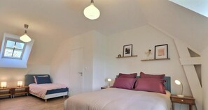 Een slaapkamer met een groot bed, twee nachtkastjes met lampen, een raam en een deur.