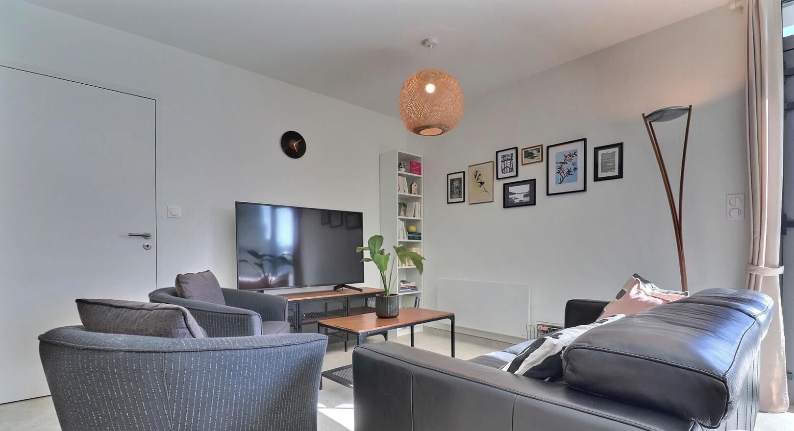 A modern living room with a flat-screen TV, a sofa, a coffee table, and a bookshelf.
