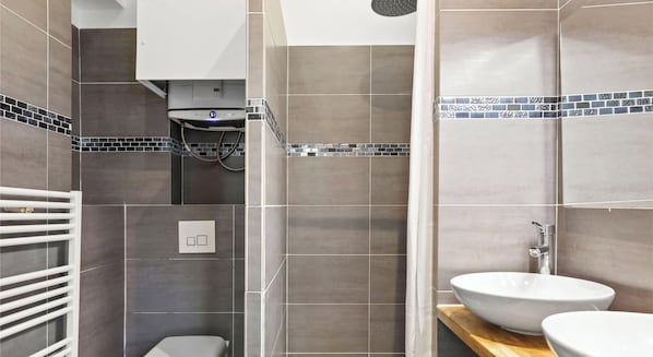 Et badeværelse med brusebad, toilet og håndvask.