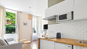 A modern kitchen with white cabinets, a microwave, and a coffee machine. - Suite Lumineuse en plein coeur du Marais (Paris)