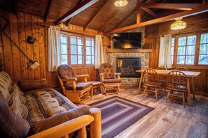 A cozy cabin interior with a stone fireplace, wooden furniture, and large windows. - Hidden gem: The Chipmunk Cabin (Babbitt)