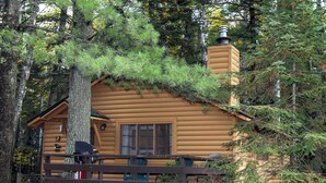Eine Blockhütte mit Schornstein, einer Veranda und einem Fenster.