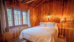 Una habitación con paneles de madera, una cama, una ventana y una lámpara.