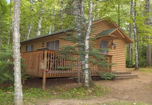 A log cabin with a wooden deck, surrounded by trees. - The Partridge Cabin at Timber Bay (Babbitt)