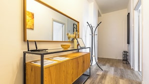 A hallway with a wooden console table, a mirror, a coat rack, and a door. - In Turin bright apartment, for those seeking comfort and tranquility (Torino)